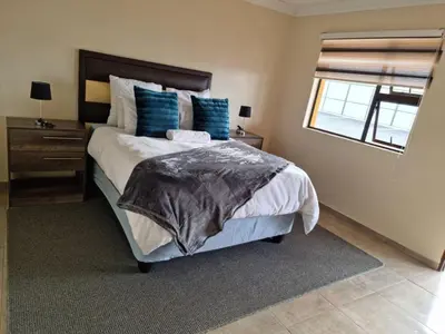 a bedroom with a large bed with blue pillows at Lasev guesthouse in Pretoria