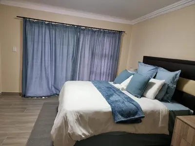 a bedroom with a large bed with blue and white pillows at Lasev guesthouse in Pretoria