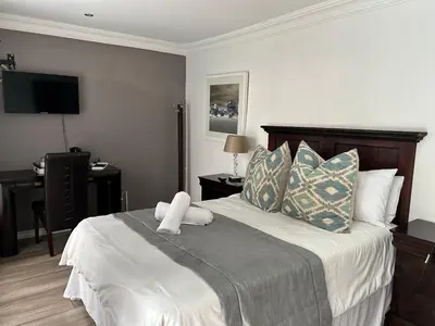 a bedroom with a bed and a desk with a television at Lebamboo On Protea in Pretoria