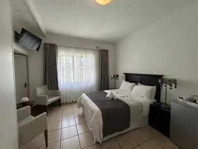 a hotel room with a bed and a chair at Lebamboo On Protea in Pretoria