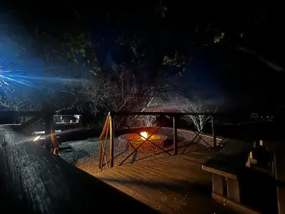 a fire pit on a deck at night at Rockfig Tented Camp in Assen