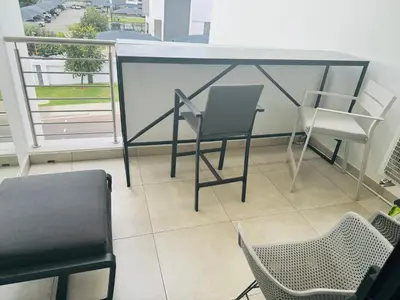 a room with chairs and a table on a balcony at Luxury 3 Bedroom Apartment in Carlswald in Erand