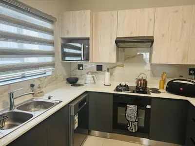 a kitchen with a sink and a stove top oven at Luxury 3 Bedroom Apartment in Carlswald in Erand