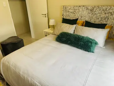 a white bed with faux fur pillows on it at Luxury 3 Bedroom Apartment in Carlswald in Erand