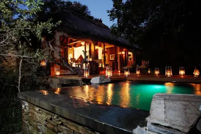 a house with a swimming pool at night at Jabulani Safari Relais & Chateaux in Kapama Private Game Reserve