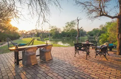 a brick patio with a table and chairs next to a lake at Jabulani Safari Relais & Chateaux in Kapama Private Game Reserve