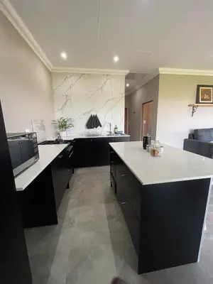 a large kitchen with black cabinets and white counter tops at Sorgenfri farm stay in Hendrina