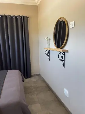 a bedroom with a bed and a mirror on the wall at Sorgenfri farm stay in Hendrina
