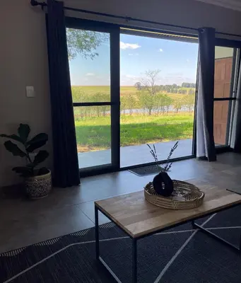 a living room with a table and a large window at Sorgenfri farm stay in Hendrina