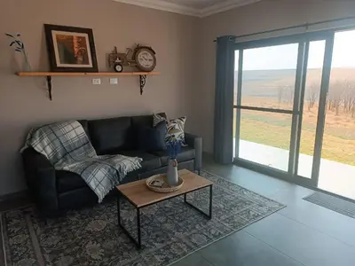a living room with a couch and a table at Sorgenfri farm stay in Hendrina