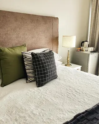 a bedroom with a bed with pillows on it at Waterlily Cove Guesthouse in Pretoria