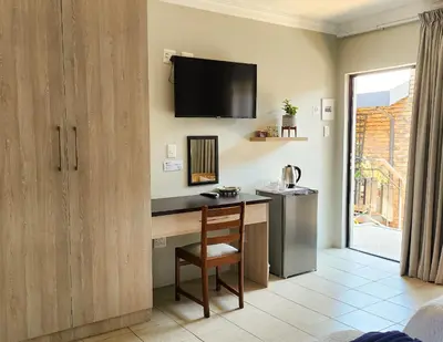 a room with a desk and a television on the wall at Waterlily Cove Guesthouse in Pretoria