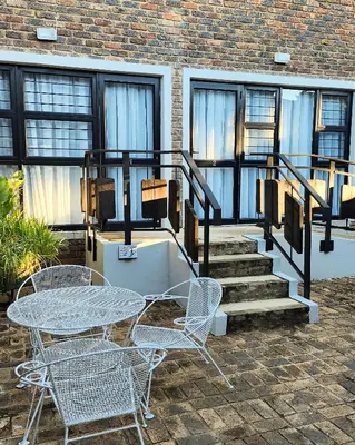 a patio with a table and chairs and stairs at Waterlily Cove Guesthouse in Pretoria