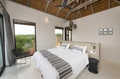 a bedroom with a large bed and a large window at Villa Zazu in Hoedspruit