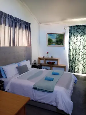 a bedroom with a large bed with blue towels on it at Zenith Guesthouse in Pretoria
