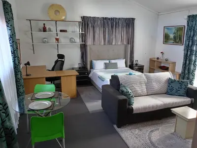 a bedroom with a bed and a couch and a table at Zenith Guesthouse in Pretoria