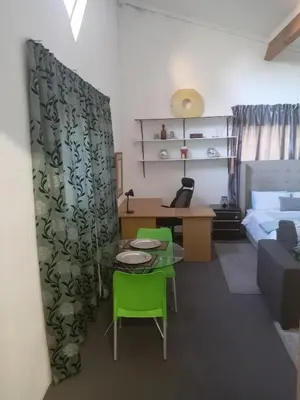 a living room with a bed and a table and chairs at Zenith Guesthouse in Pretoria