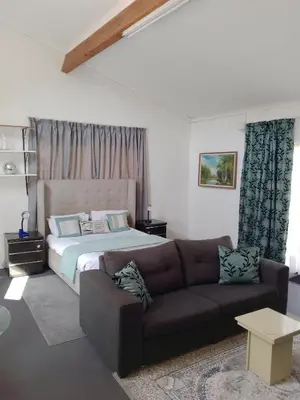 a living room with a bed and a couch at Zenith Guesthouse in Pretoria