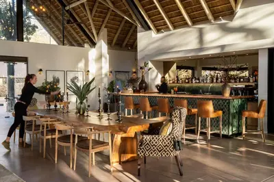 a woman standing at a table in a restaurant at Monwana in Thornybush Game Reserve