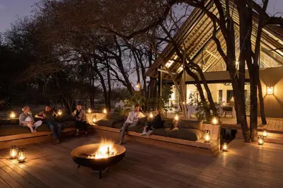 a group of people sitting on couches on a patio at night at Monwana in Thornybush Game Reserve