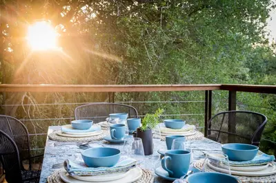 a table with blue cups and plates on a porch at Serondella Safari Lodge in Thornybush Game Reserve