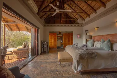 a bedroom with a large bed and a living room at Waterbuck Game Lodge Thornybush Nature Reserve in Thornybush Game Reserve