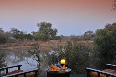 a table with a candle on it next to a river at Waterbuck Game Lodge Thornybush Nature Reserve in Thornybush Game Reserve