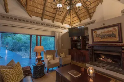 a living room with a fireplace and a tv at Waterbuck Game Lodge Thornybush Nature Reserve in Thornybush Game Reserve