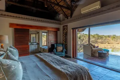 a bedroom with a large bed and a large window at Waterbuck Game Lodge Thornybush Nature Reserve in Thornybush Game Reserve
