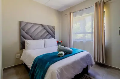 a bedroom with a bed with a stuffed animal on it at The Waterfall Nest 2 Bedroom Apartment in Midrand