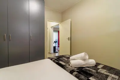 a bedroom with a large white bed and a mirror at The Waterfall Nest 2 Bedroom Apartment in Midrand