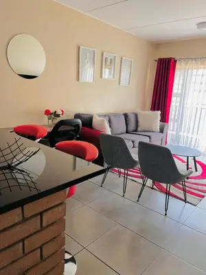a living room with a couch and a table and chairs at The Waterfall Nest 2 Bedroom Apartment in Midrand