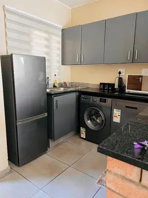 a kitchen with a refrigerator and a washing machine at The Waterfall Nest 2 Bedroom Apartment in Midrand