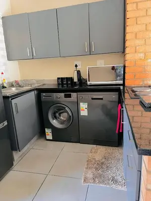 a kitchen with a washing machine and a sink at The Waterfall Nest 2 Bedroom Apartment in Midrand