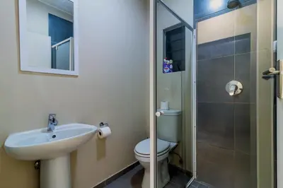 a bathroom with a toilet and a sink and a shower at The Waterfall Nest 2 Bedroom Apartment in Midrand
