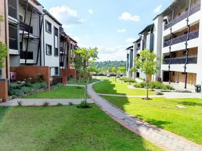 an empty courtyard of an apartment building with trees and grass at The Waterfall Nest 2 Bedroom Apartment in Midrand