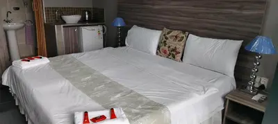 a large bed with white sheets and red shoes on it at FUMODS guest house in Pretoria