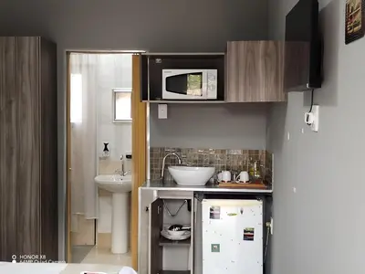 a small kitchen with a microwave and a refrigerator at FUMODS guest house in Pretoria