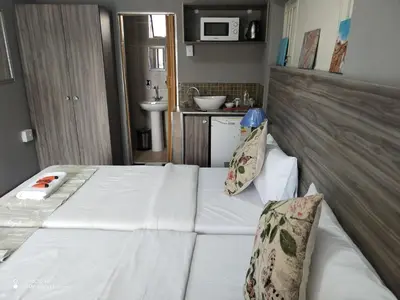 a small room with a bed and a kitchen at FUMODS guest house in Pretoria