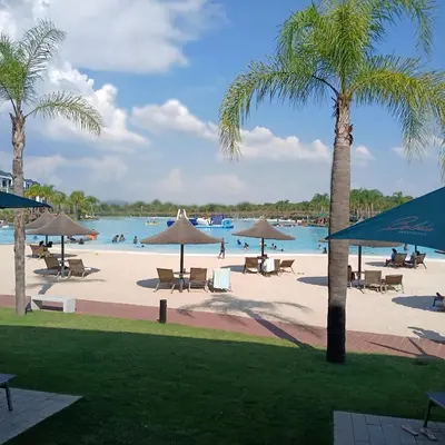 a beach with chairs and umbrellas and a body of water at The Blyde: 2-Bed Luxe Apartment in Pretoria