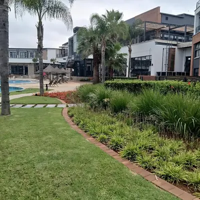 a walkway in front of a resort with palm trees at The Blyde: 2-Bed Luxe Apartment in Pretoria