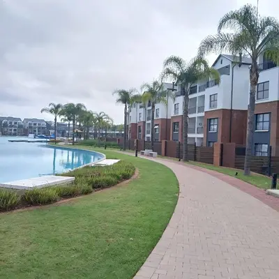 a walkway next to a pool with palm trees at The Blyde: 2-Bed Luxe Apartment in Pretoria