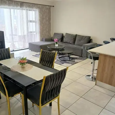 a living room with a couch and a table and chairs at The Blyde: 2-Bed Luxe Apartment in Pretoria
