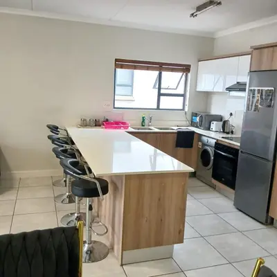 a kitchen with a counter and some chairs in it at The Blyde: 2-Bed Luxe Apartment in Pretoria