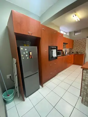 a kitchen with wooden cabinets and a stainless steel refrigerator at AfricaLove on Tiger Suite in Pretoria