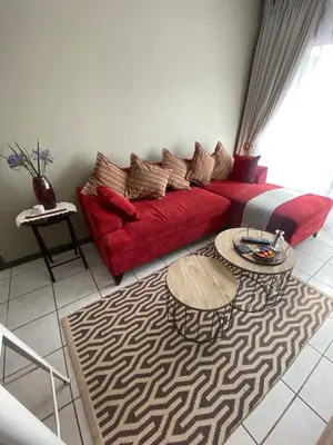 a living room with a red couch and a table at AfricaLove on Tiger Suite in Pretoria