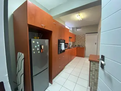 a kitchen with wooden cabinets and a stainless steel refrigerator at AfricaLove on Tiger Suite in Pretoria