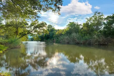 a river with trees and clouds in the water at Malaga Hotel in Panorama