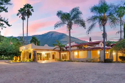 a house with palm trees and a mountain in the background at Malaga Hotel in Panorama