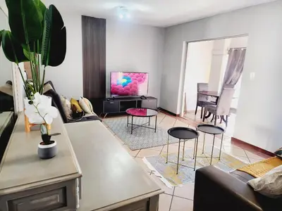 a living room with a couch and chairs and a tv at Lemon tree in Pretoria
